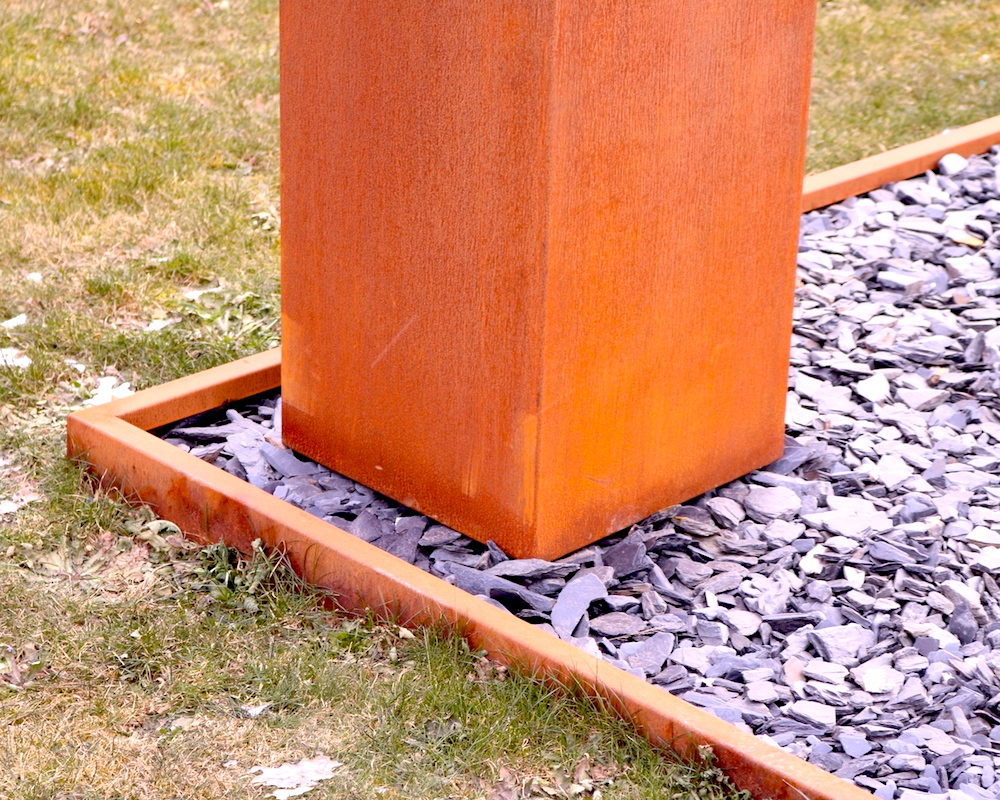 Bordure en acier Corten de Kubik Création délimitant une jardinière verticale et des galets décoratifs