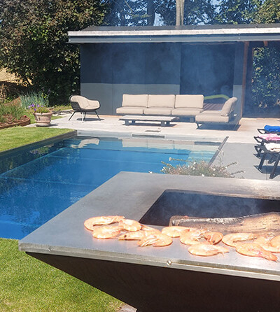 Plancha en Acier Corten avec des écrevisses qui sont grillées près d'une piscine et d'un salon de jardin moderne